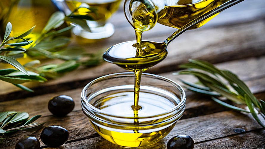 Pouring extra virgin olive oil in a glass bowl